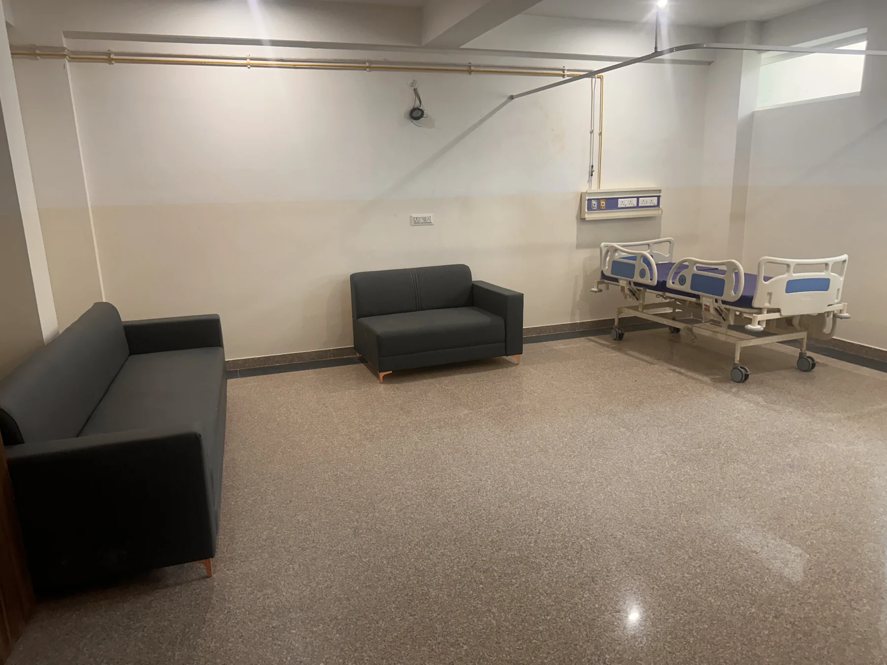 Hospital waiting area with family seating and a patient bed